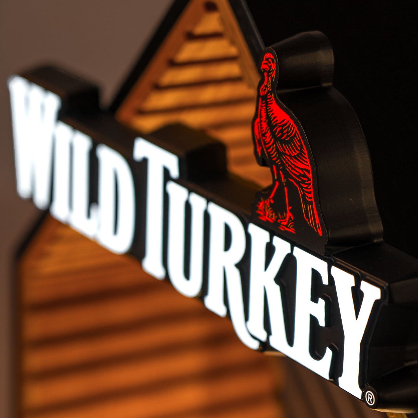 Close up shot of illuminated Wild Turkey logo with a red turkey on a wooden background.