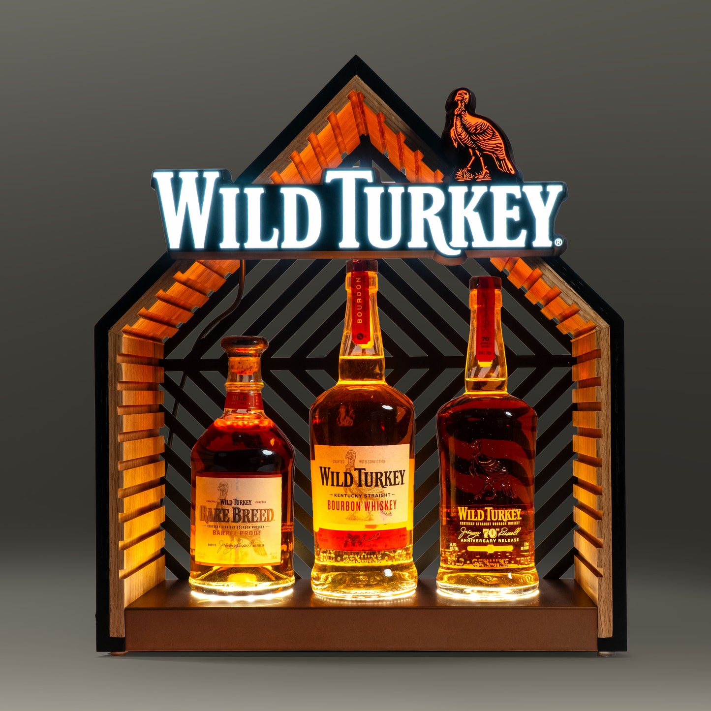 Three bottles of Wild Turkey bourbon in an illuminated bottle glorifier. 