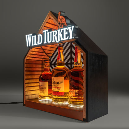 Three bottles of Wild Turkey bourbon in an illuminated bottle glorifier. 